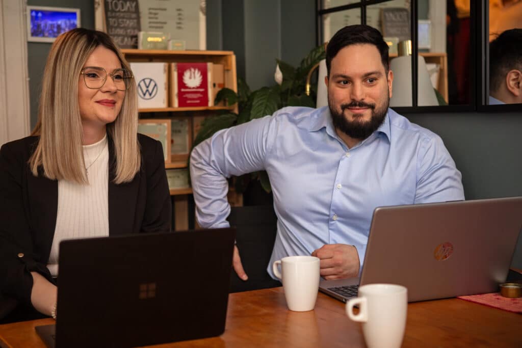 Bilden visar två personer från IT support Stockholm som sitter vid sina laptop datorer.